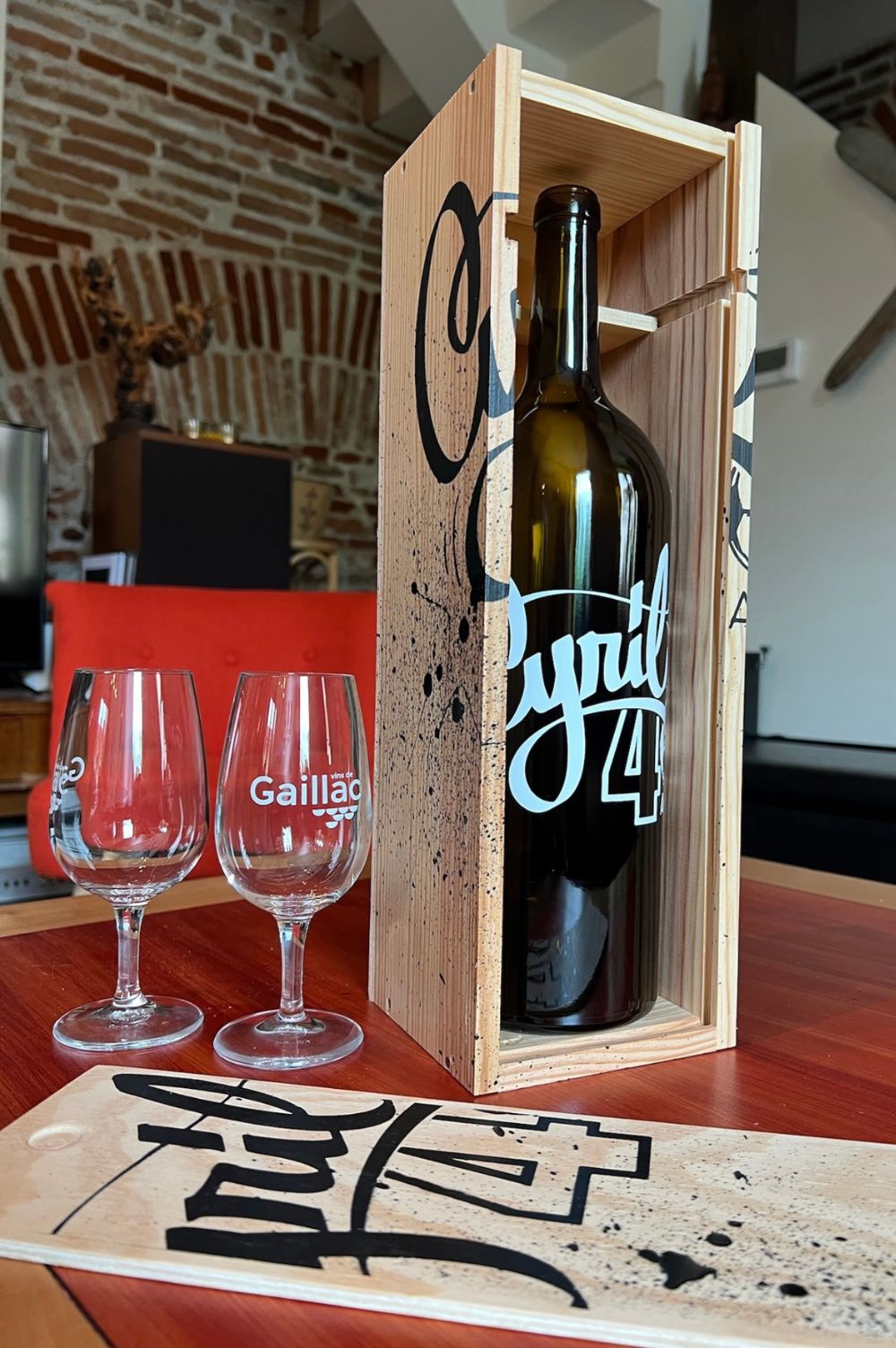 deux verres à vin de Gaillac à côté de la bouteille de vin dans son coffret personnalisé.