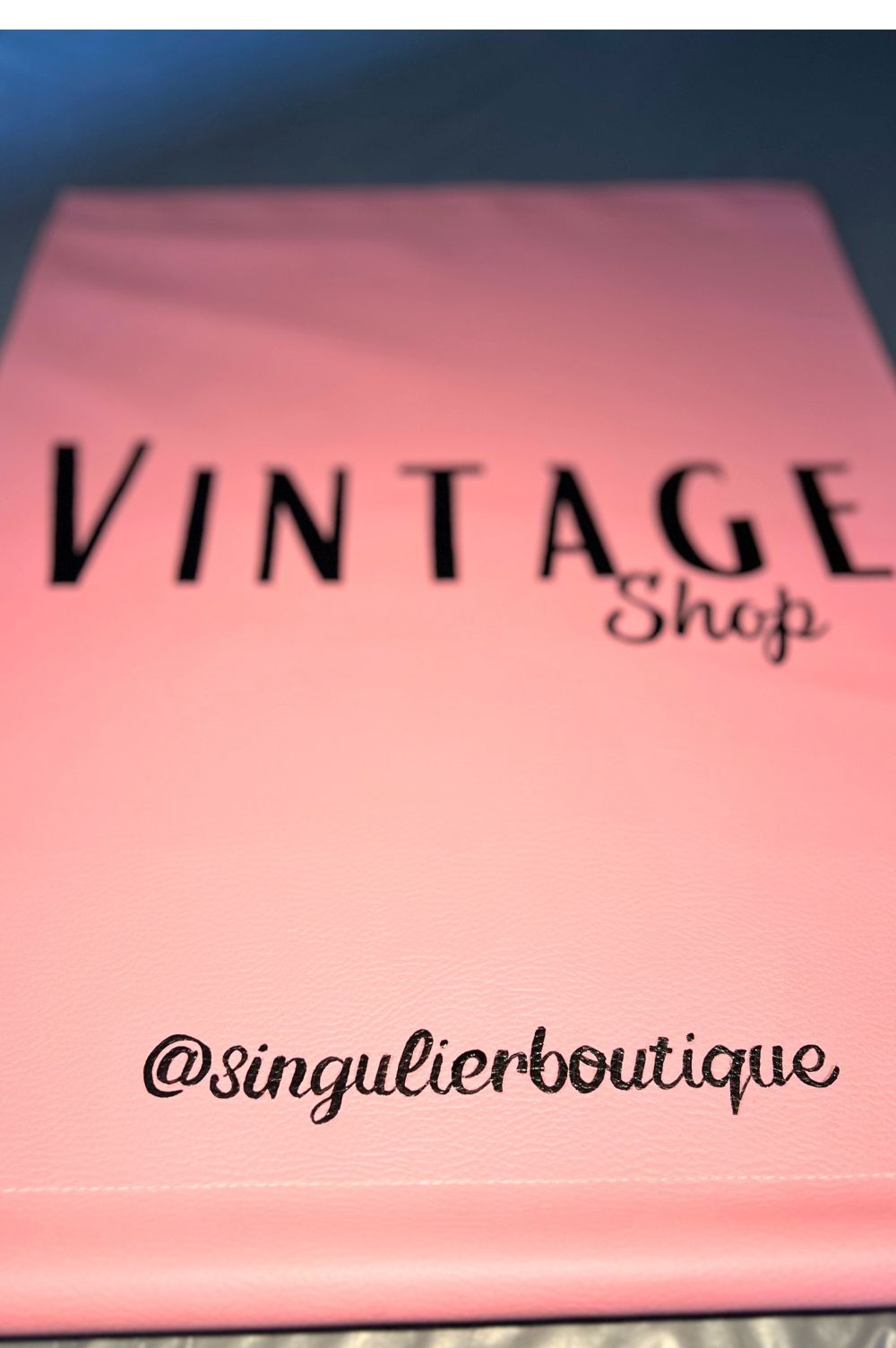 zoom sur l'enseigne drapeau rose de la friperie Singulier, avec l'inscription VINTAGE SHOP et en bas @singulierboutique