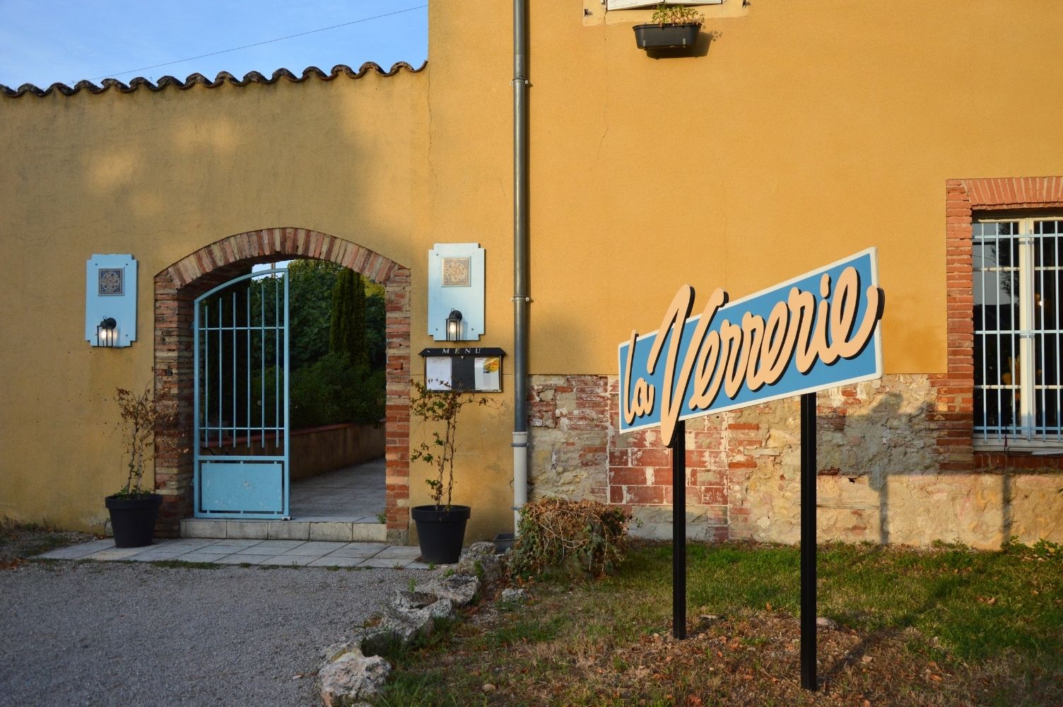 Panneau enseigne portant l'inscription La Verrerie devant l'entrée de l'hôtel restaurant.