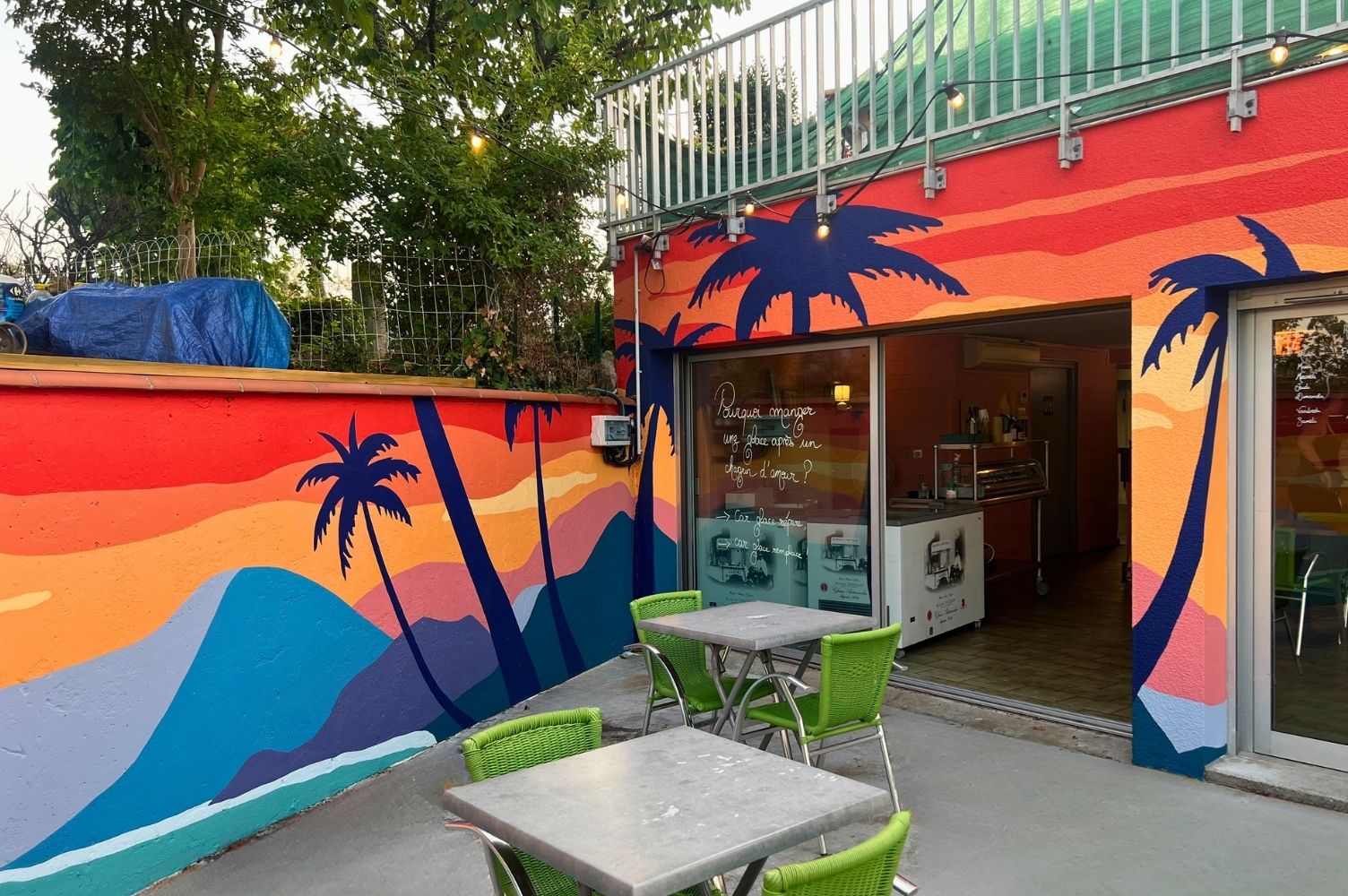 un décor de plage peint sur le mur d'un bar de plage avec des palmiers au coucher du soleil