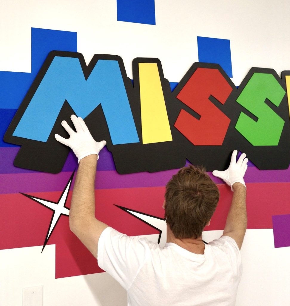 Paul place les lettres qu'il a peintes à la main sur le mur de l'entreprise Skillz